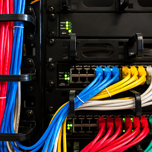 Computer Networking - Groups of different coloured network cables plugged into the back of a rack mounted server.